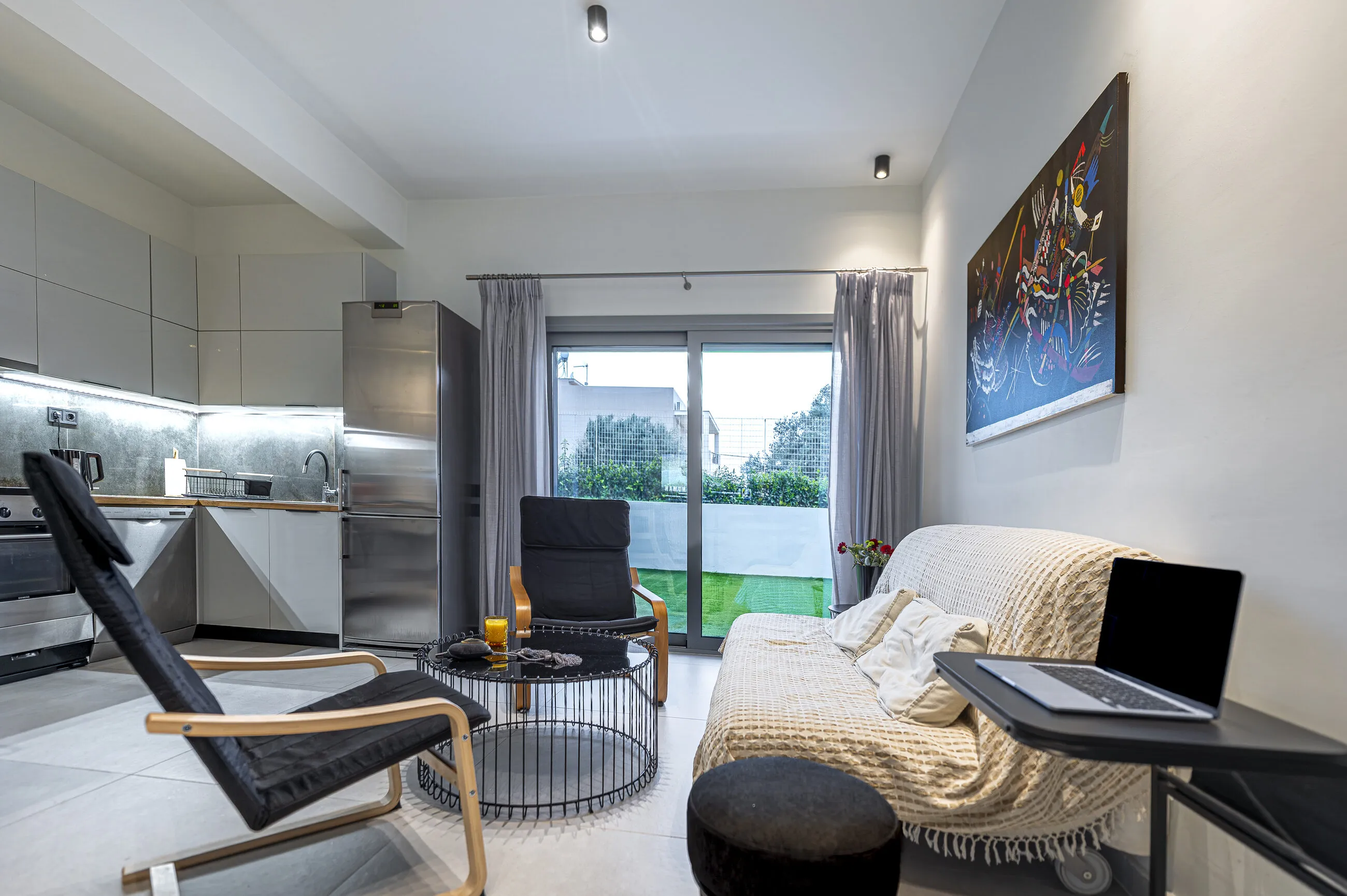 Living area with a large sofa, 55-inch smart TV and a desk by the window
